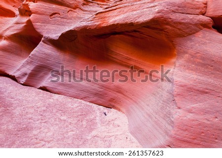 Carved sandstone rock wall meets fine sand floor of Canyon X in Page, AZ.