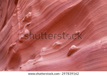 Eroded sandstone canyon walls showing ancient sand layers and standout features in abstract patterns.