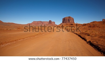 A red dirt road gives access to the impressive sandstone formations that create Monument Valley in the Navajo Nation.
