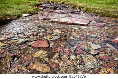 Pure, clean glacier water runs over colorful rocks in a peaceful flow at Glacier National Park, Montana.