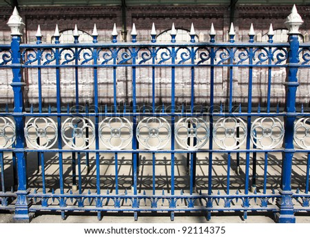 A section of royal blue cast iron fencing decorated with ornate silver circles and spikes at Darlington Railway Station, England.