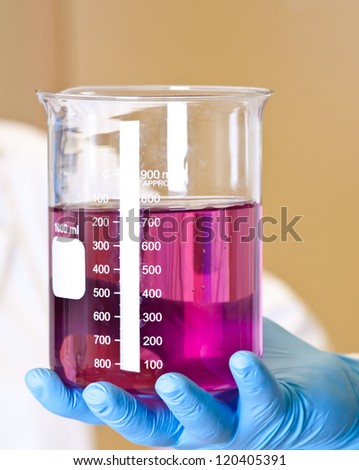 Scinetist Hand holding Chemistry lab beaker with permanganate