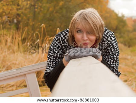 Portrait of a young blonde woman of Caucasian appearance with gloves and coat with funny grimace in autumn outdoors