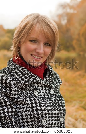 Portrait of a smiling young woman blonde Caucasian appearance in coat in autumn outdoors