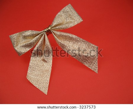 A metallic gold bow on a red background
