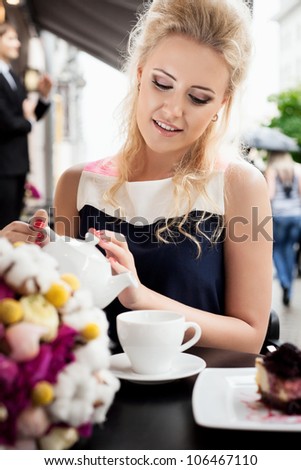 A young woman is pouring tea. Holding a cup of tea. Outdoors