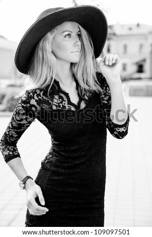 Portrait of beautiful young girl standing in black sun hat outdoors