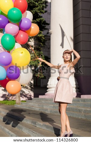 Young girl with colorful latex balloons looking at the sun, urban scene, outdoors