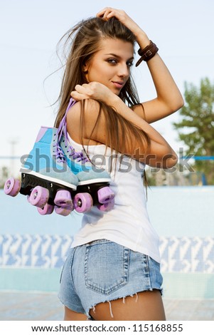 Photograph of a roller derby sexy woman holding her skates by the laces, outdoors