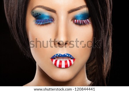 Woman beautiful face with perfect makeup on black background. on the lips and eyes painted an American flag