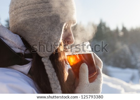 girl drinks tea over winter nature background outdoor