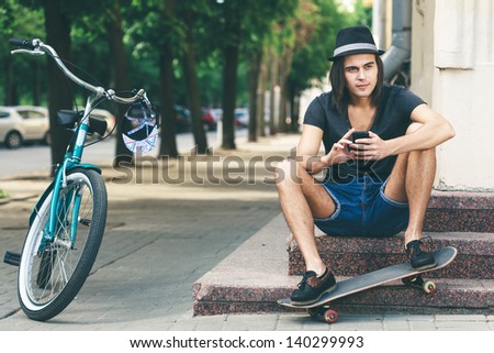 Happy skateboarder sitting on stairs. Young active people. Outdoors