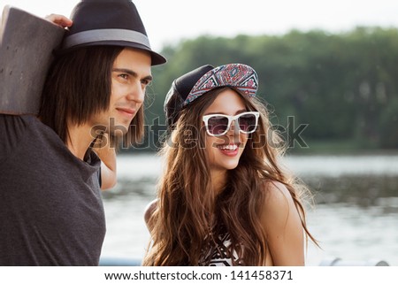 Couple looking away on the bank of a river. Young active people. Outdoors, lifestyle