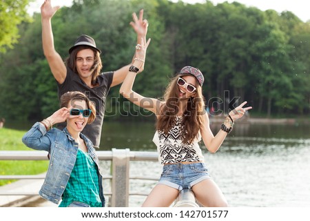 Young active people. Two young girls and one guy having fun near the river. Outdoors, lifestyle