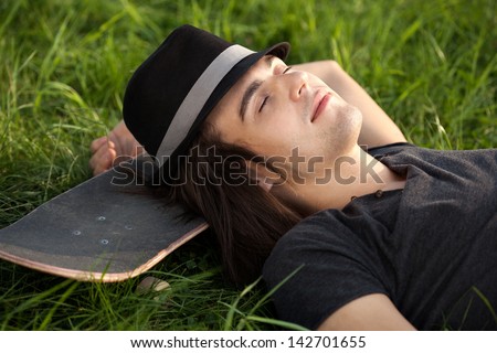 Young caucasian man lying down on his skateboard. Outdoor, lifestyle