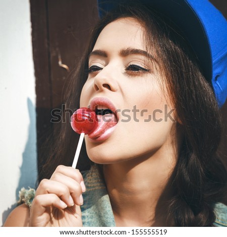 Young sensual girl sucking lollipop.  Outdoors, lifestyle.