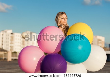 Happy young woman standing  with big colorful latex balloons. Outdoors, lifestyle