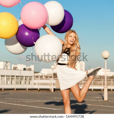 Happy young smiling girl having fun with big colorful latex balloons.  Gorgeous thick wavy hair. Outdoors, lifestyle
