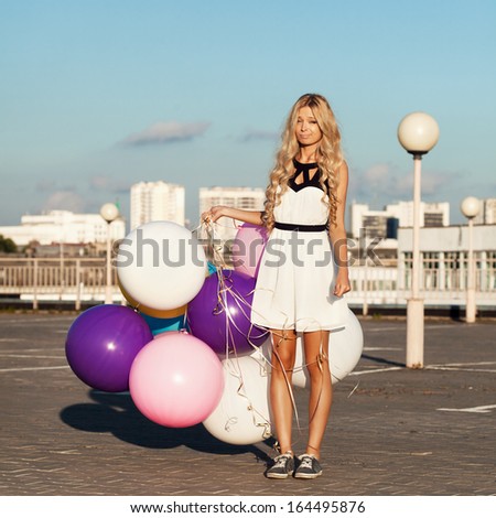 Sad young woman with colorful latex balloons.  Outdoors, lifestyle
