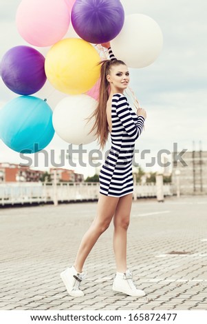 Happy young beautiful woman with colorful latex balloons. Outdoors, lifestyle