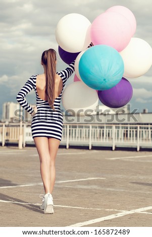 Happy young woman  with big colorful latex balloons. Girl going back to the camera. Outdoors, lifestyle