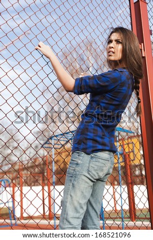 Portrait of a beautiful girl hipster. Trendy young naughty woman holding at the net. Outdoors, lifestyle.