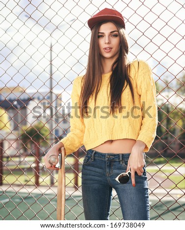 Beautiful young girl  hipster standing with longboard near playground in the afternoon. Skateboarding. Outdoors, lifestyle
