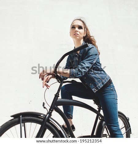 Young woman hipster standing with black bike. Outdoor lifestyle portrait