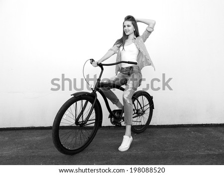 Young hipster girl with black bike having fun. Outdoor lifestyle portrait