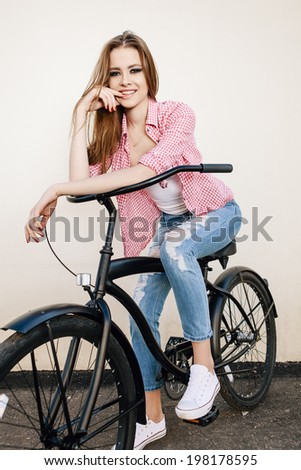Young hipster girl with black bike looking at camera. Outdoor lifestyle portrait
