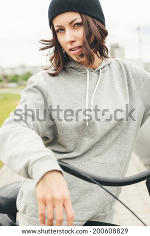 Young hipster girl with black bike looking at camera. Outdoor lifestyle portrait