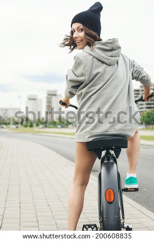 Young hipster girl with black bike back to camera. Outdoor lifestyle portrait