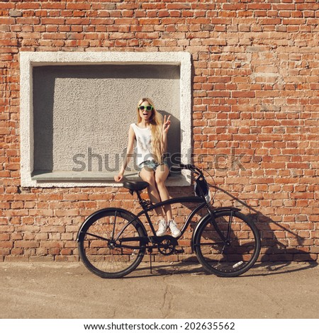 Young woman with city bicycle near brick wall. Outdoor lifestyle portrait of girl
