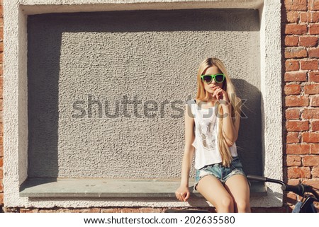Young woman near brick wall. Outdoor lifestyle portrait of girl