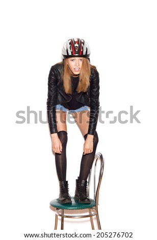 Funky girl in a bicycle helmet standing on stool and showing biker. White background, not isolated