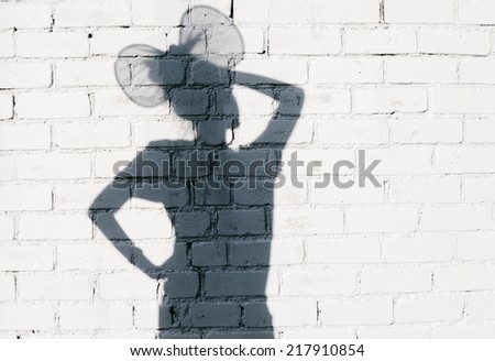 Funky girl fooling around on the brick wall background. Photo of shadows of woman with ears