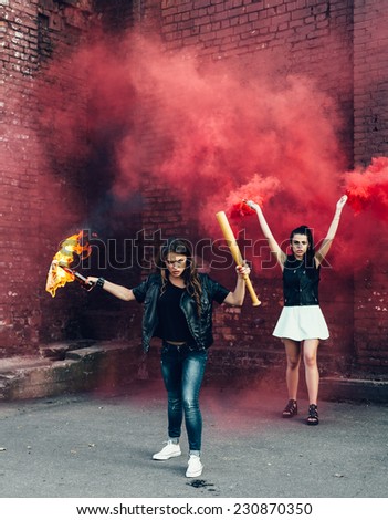 Two Bad girls with Molotov cocktail and red smoke bomb in the street.  Outdoor lifestyle portrait