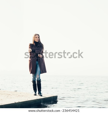 Outdoor portrait of young pretty woman posing near the sea alone and waiting