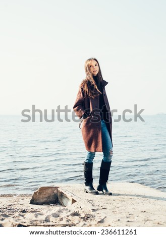 Outdoor portrait of young pretty woman posing near the sea alone and waiting