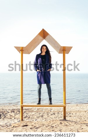 Outdoor portrait of young pretty woman posing near the sea alone, standing and waiting