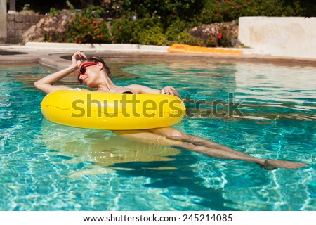 Young pretty fashion woman body posing in summer in pool with clear water lying inner tube and having fun