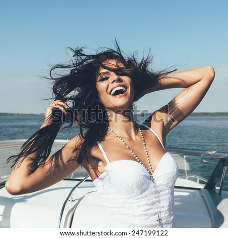 Young happy woman have fun on the luxury boat in open sea in summer. Caucasian female model