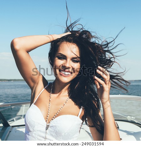 Young happy woman have fun on the luxury boat in open sea in summer. Caucasian latin female model