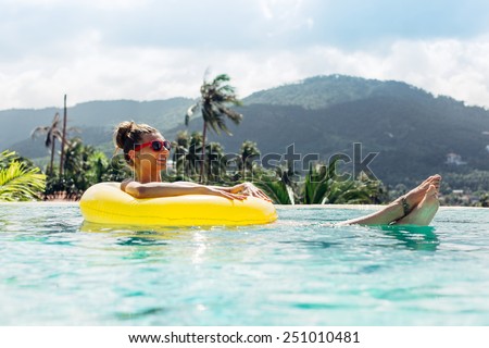 Young pretty fashion woman body posing in summer in pool with clear water lying inner tube and having fun
