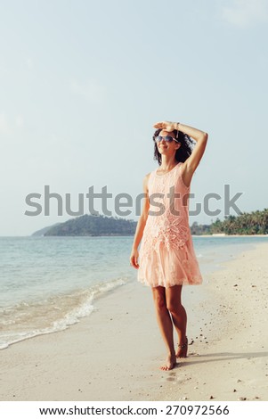 Young fashion woman walking on the beach and looking on the water and waiting for somebody in ocean. Outdoors lifestyle portrait