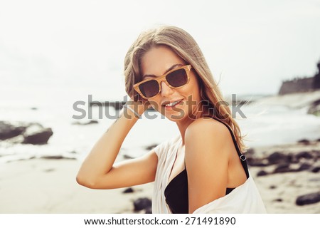 Outdoor summer beach tropic portrait of young sexy sensual tanned sport woman in  sunglasses posing on the sea in sunny weather and have fun in vacation time