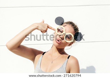 Stylish fashion blonde sexy young girl in sunglasses   gun shows.  White background, not isolated