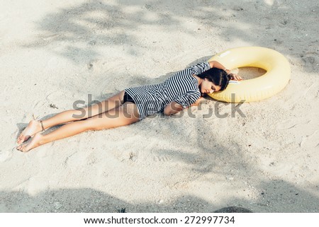 Beautiful woman in bikini lying on a beach in sand at summer day. Outdoor lifestyle portrait