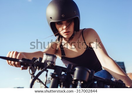 Biker girl in helmet sitting on vintage custom motorcycle. Outdoor lifestyle portrait