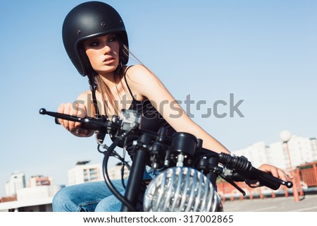 Biker girl in helmet sitting on vintage custom motorcycle. Outdoor lifestyle portrait